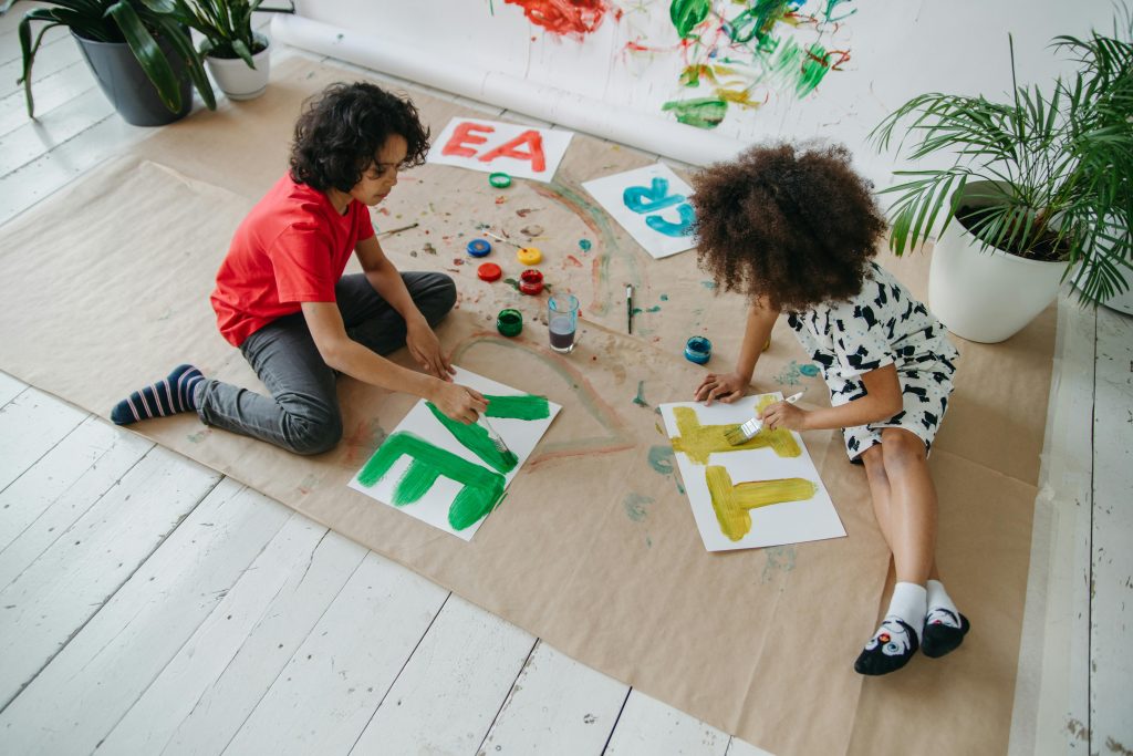 Children enjoying creativity with paints and brushes in an indoor setting, encouraging artistic expression.